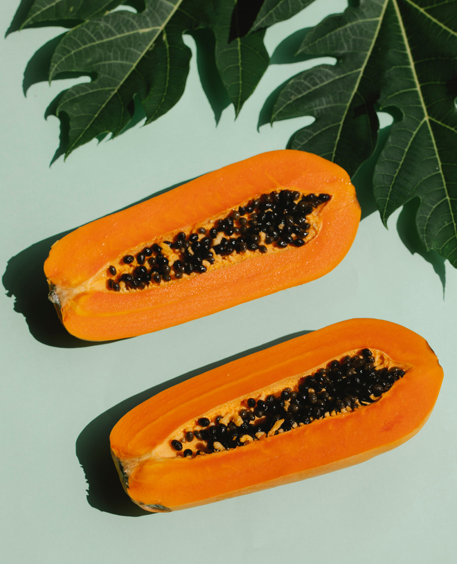 Halved ripe orange papaya on blue background